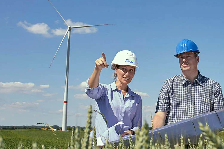 Zwei Planer*innen mit Windrad im Hintergrund